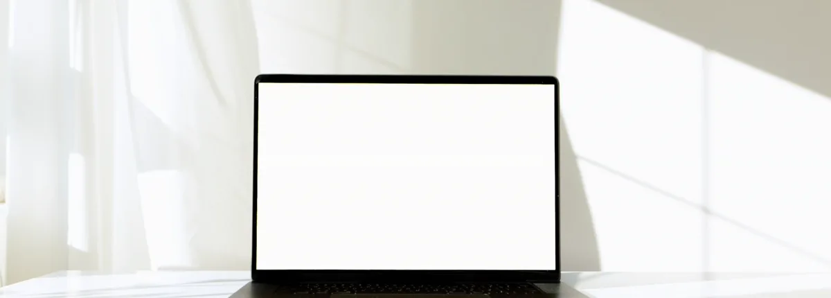 Laptop auf einem hellen Tisch, der Bildschirm ist noch leer