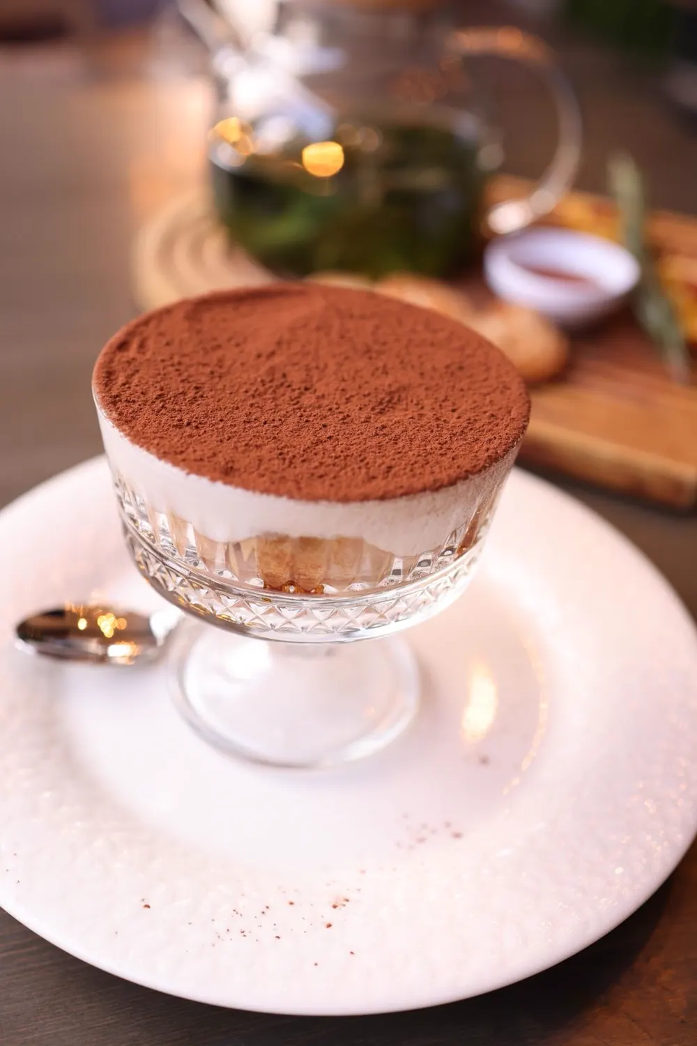 Tiramisù im Glas, mit Kakao bestäubt, auf einem weißen Teller
