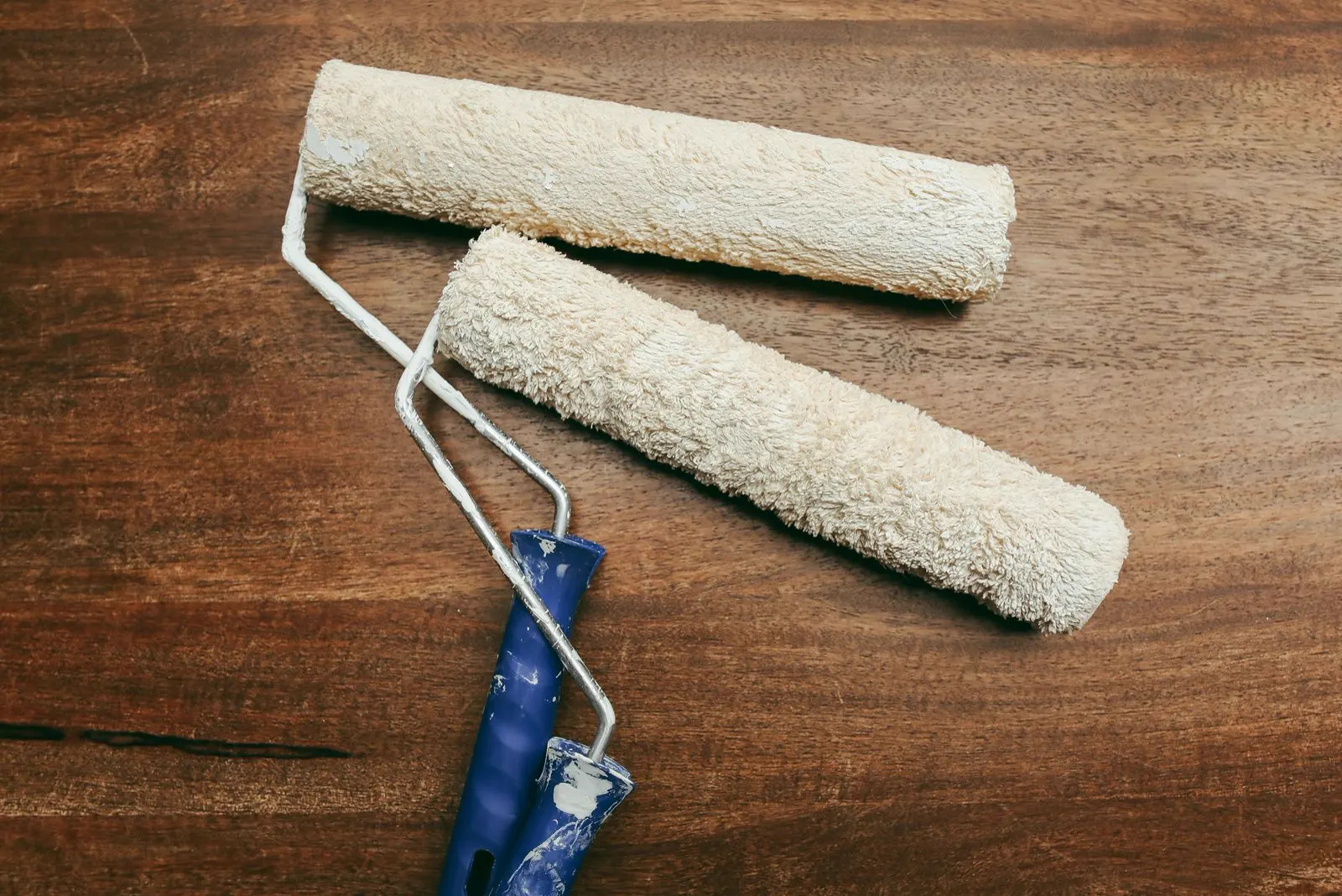 Zwei gebrauchte Farbrollen auf einem Holztisch