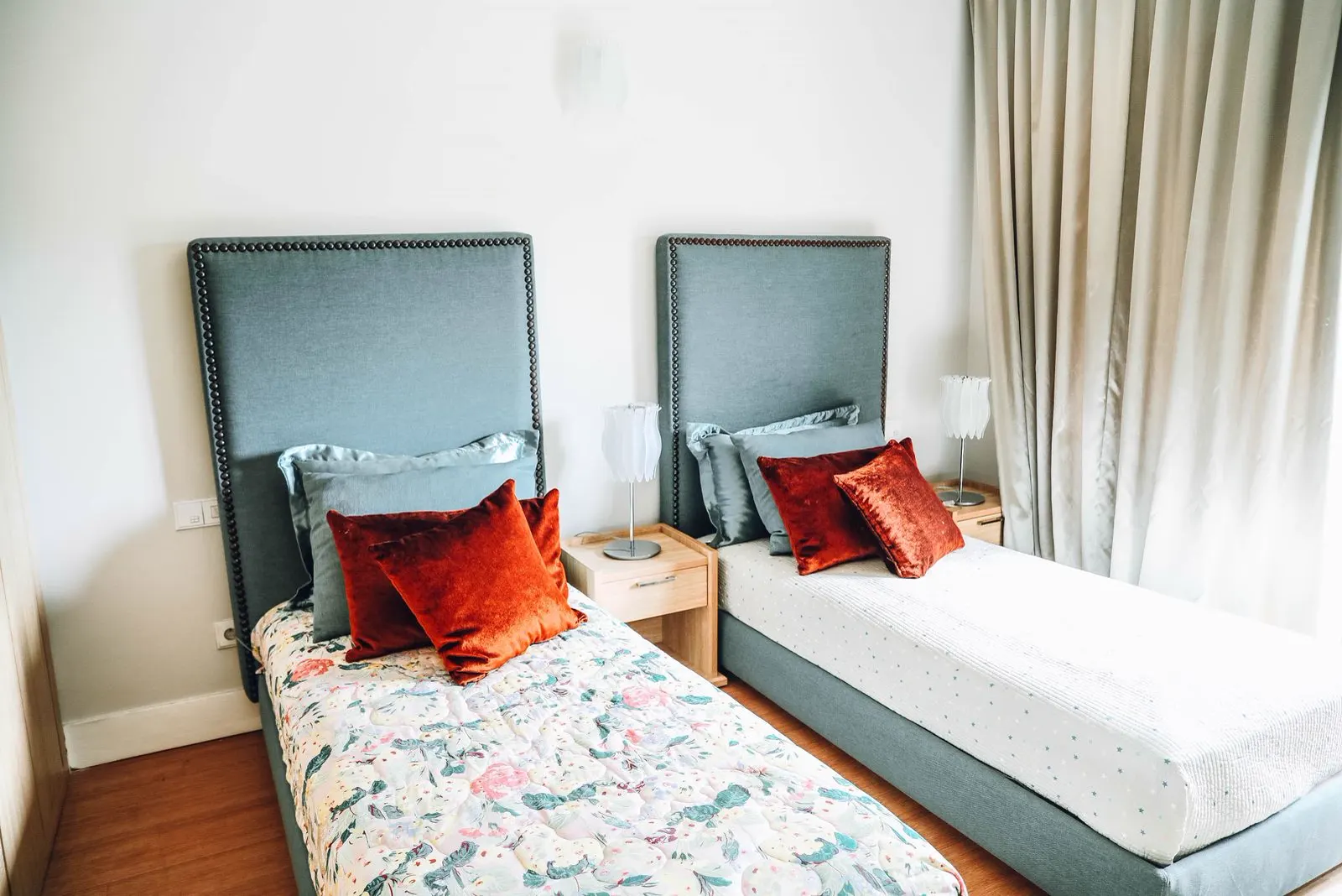 Zimmer mit zwei Betten, gepolsterten Kopfteilen und roten Kissen