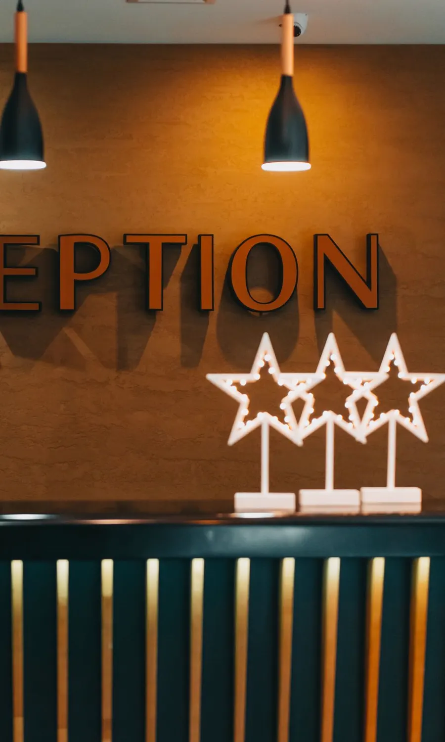 Rezeption mit Leuchtschrift an der Wand und drei Sternen auf dem Tresen